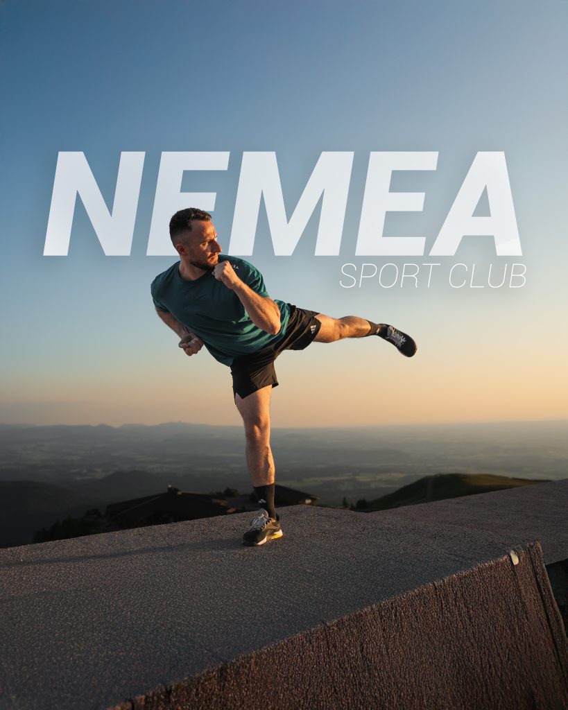 Homme pratiquant le kickboxing au coucher de soleil – Nemea Sport Club Homme effectuant un mouvement de kickboxing devant un ciel au coucher du soleil, avec le logo Nemea Sport Club flottant dans le ciel
