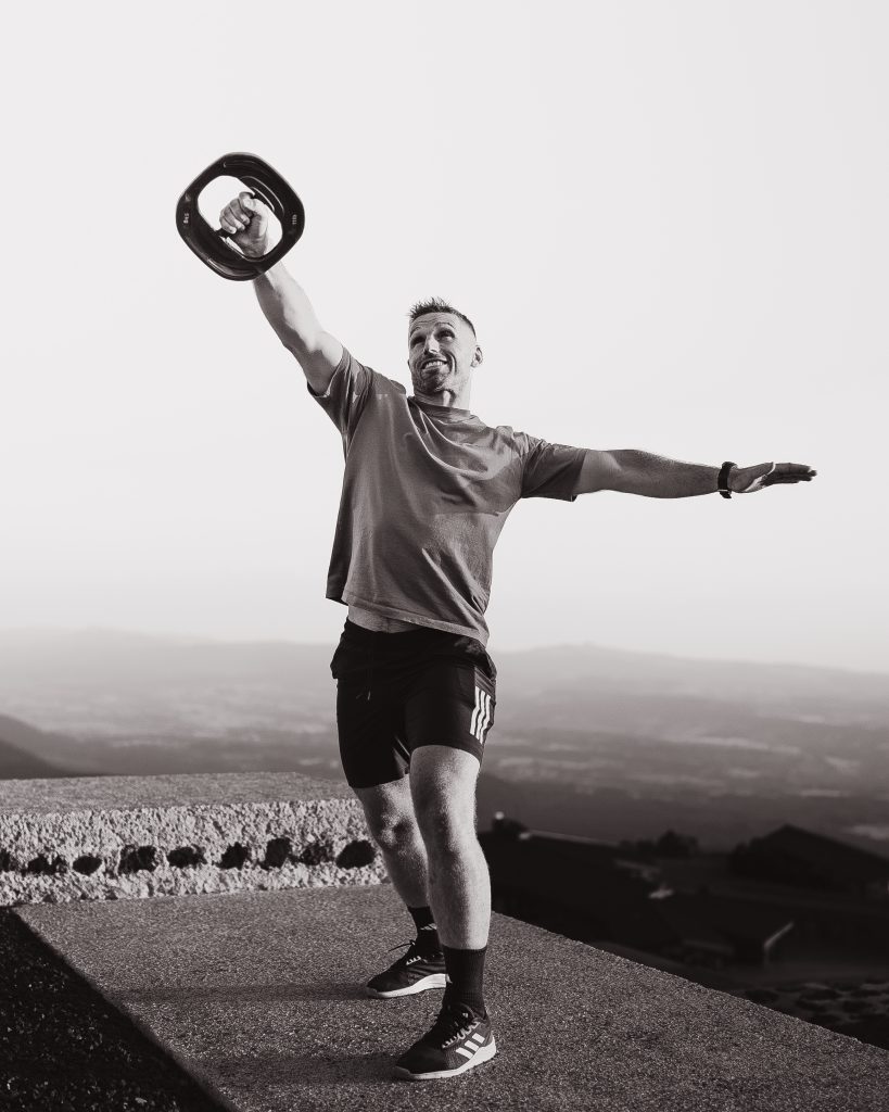 homme en noir et blanc soulevant un poid en l'air au sommet du puy de dôme homme en noir et blanc soulevant un poid en l'air au sommet du puy de dôme