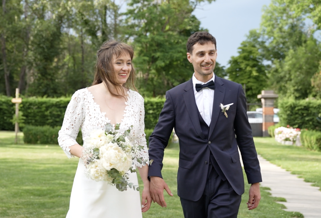 Jeune couple de marié souriant se tiennent la main dans un parc